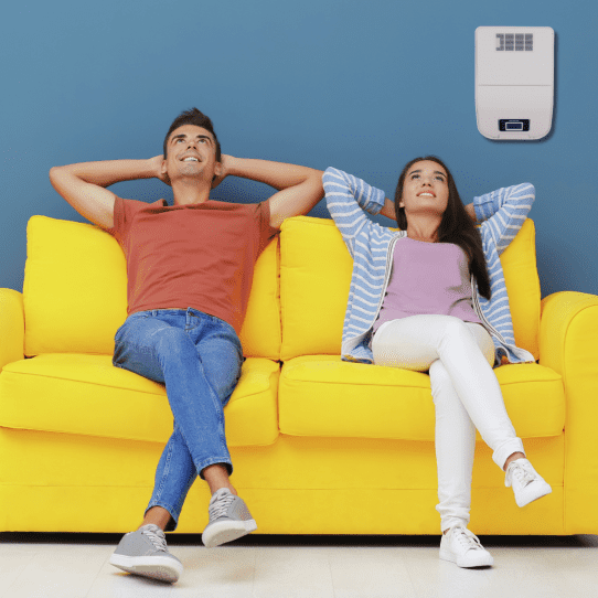 Paar sitzt auf dem Sofa mit einem Luftbehandlungssystem an der Wand 