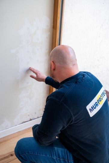Feuchtigkeitsexperte fühlt an einer feuchten Schlafzimmerwand