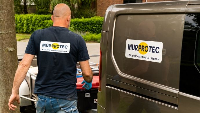 Der Feuchtigkeitsexperte von Murprotec geht an seinem Auto vorbei