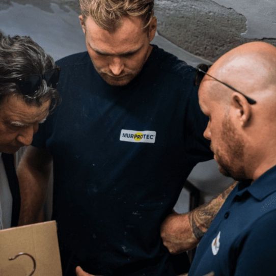 Drei Feuchtigkeitsexperten führen eine Kellerabdichtung durch. 