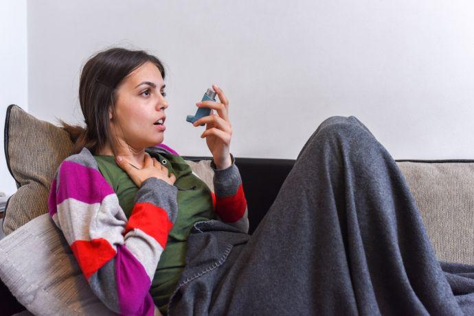 Une jeune femme asthmatique utilise un inhalateur