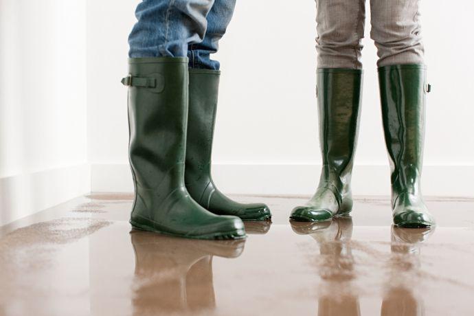 Zwei Personen stehen auf einem nassen Boden und tragen Gummistiefel