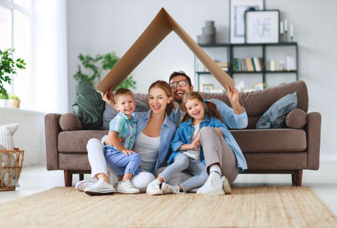 Un pÃ¨re tient un toit en carton au-dessus des tÃªtes de sa famille heureuse