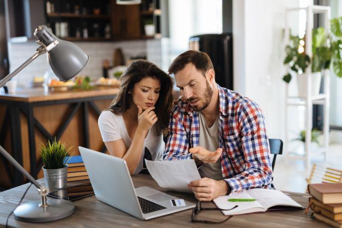 Un jeune couple frustré vérifie ses comptes sur son ordinateur portable.