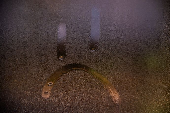 Kondensation auf dem Fenster mit einem traurigen Smiley-Gesicht