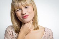 Eine Frau hat durch das Einatmen von Schimmelteilchen Halsschmerzen